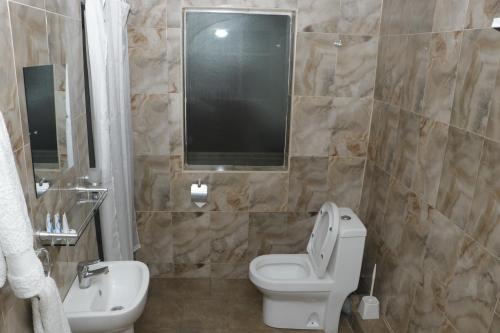a bathroom with a toilet and a sink at Motel Clavina in Gilgil