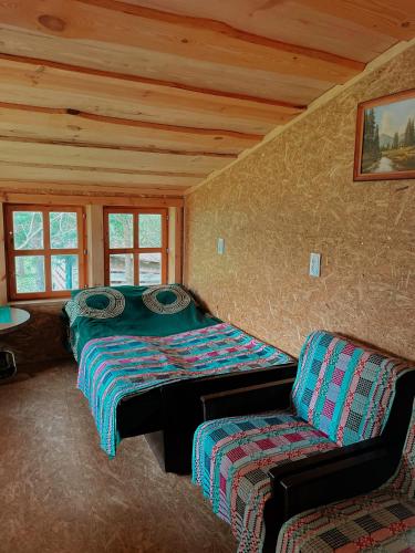 a room with two beds and a chair in a cabin at Sodyba Pas Juzi in Alanta