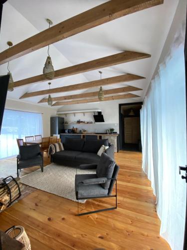 a living room with a black couch and wooden floors at Clay House in Pāvilosta