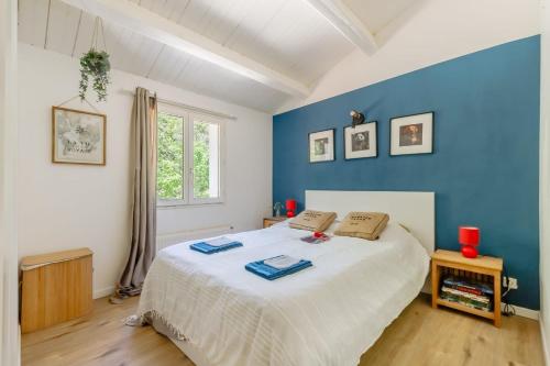 une chambre avec un grand lit blanc avec des murs bleus dans l'établissement Villa L'Eau Vive, à Saint-Jean-de-Monts