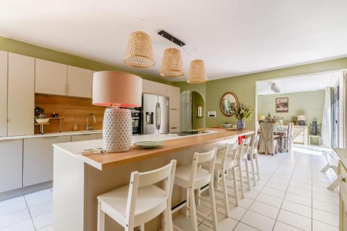 une cuisine avec des murs verts et un comptoir avec des chaises blanches dans l'établissement Villa L'Eau Vive, à Saint-Jean-de-Monts