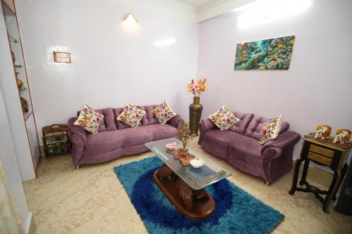 a living room with purple couches and a table at Brij Inn Guwahati in Guwahati