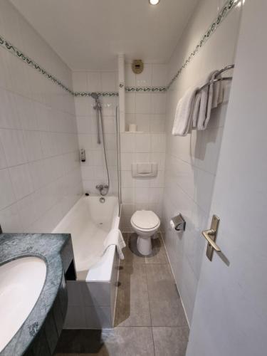 a bathroom with a tub and a toilet and a sink at Hôtel France Eiffel in Paris