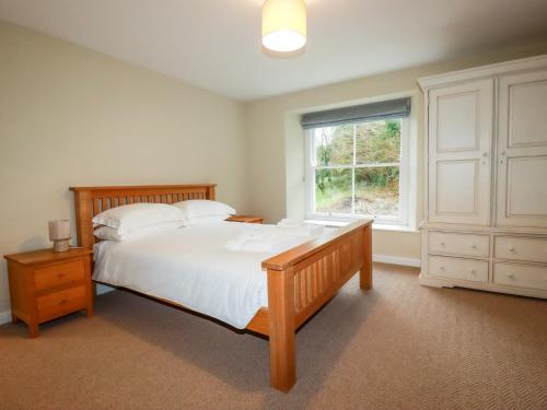 a bedroom with a large bed and a window at Tretoil Farm House in Bodmin