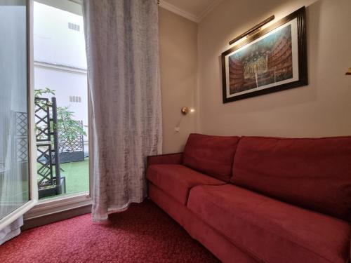 a living room with a red couch and a window at Hôtel France Eiffel in Paris
