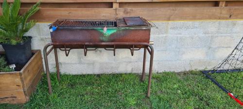 un grill assis dans l'herbe à côté d'une clôture dans l'établissement Villa OyamaÏ, à Bénesse-Maremne