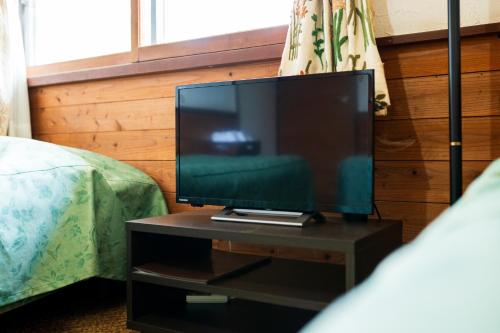 a flat screen tv sitting on a table next to a bed at Pension Yufuin in Yufuin