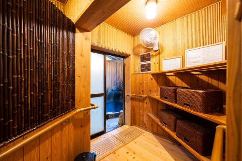 a room with wooden walls and a hallway with baskets at Pension Yufuin in Yufuin