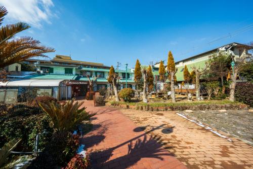 a courtyard with palm trees and a building at Pension Yufuin in Yufuin