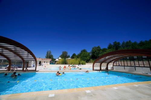 une grande piscine avec des gens dans l'eau dans l'établissement H des Lacs Cottage 2 pers, à Monclar-de-Quercy