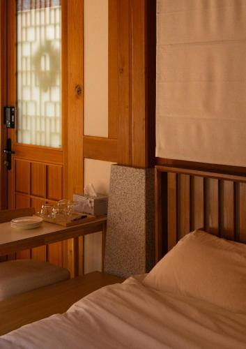 a bedroom with a bed and a table and a window at Yeoyeoje - Hanok Accommodation with the atmosphere of Hwaseong Fortress Road in Suwon, a UNESCO World Heritage in Suwon