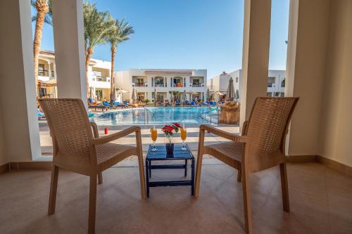 a living room with a table and two chairs and a pool at Xperience St. George Sharm El Sheikh in Sharm El Sheikh