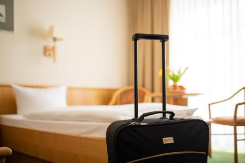 a suitcase is standing in front of a bed at Park Hotel Sellin in Ostseebad Sellin