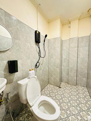 a bathroom with a toilet and a phone on the wall at Dedbaicha cafe & Hostel Phuket old town in Phuket