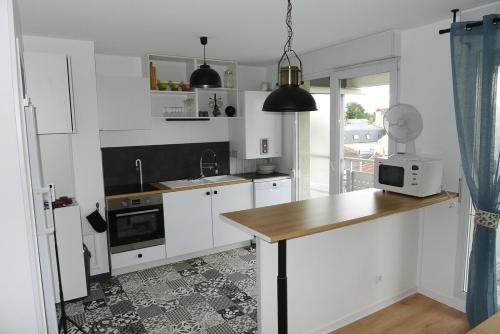 une cuisine avec des placards blancs et un comptoir avec un four micro-ondes dans l'établissement Appartement Venise 2 chambres, à Reims