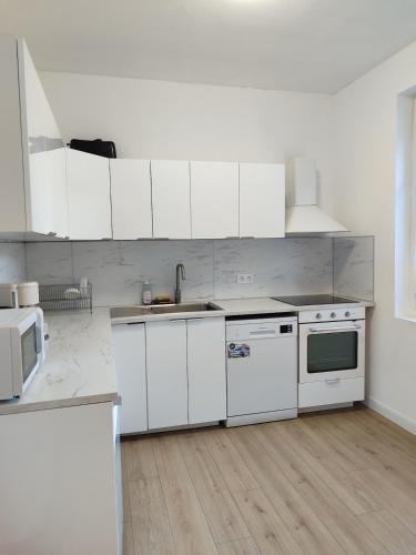 une cuisine avec des armoires blanches et des appareils électroménagers blancs dans l'établissement Logement entier - Centre Fécamp - 67 Vanessa, à Fécamp
