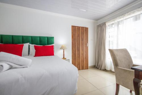 Un dormitorio con una gran cama blanca con almohadas rojas. en Safi 1 bedroom Suite 9, en East London