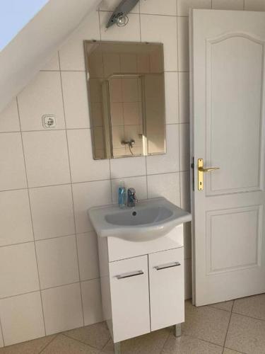 a bathroom with a sink and a mirror and a door at Zámor 10 Apartmant in Keszthely