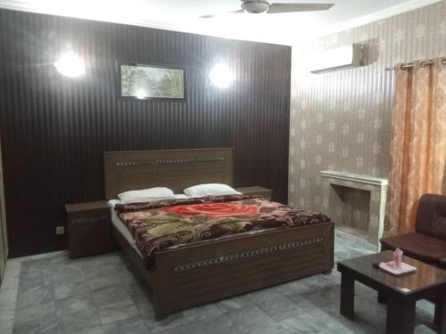 a bedroom with a bed and a chair at Star Hotel Lahore in Lahore