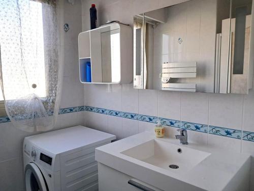 une salle de bain avec un lavabo et une machine à laver dans l'établissement Le Beachcomber, à Antibes