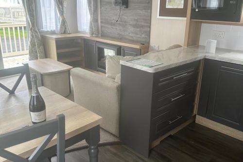 a living room with a couch and a table with a bottle of wine at Charming 5-Beds Caravan in beautiful Seton Sands in Port Seton
