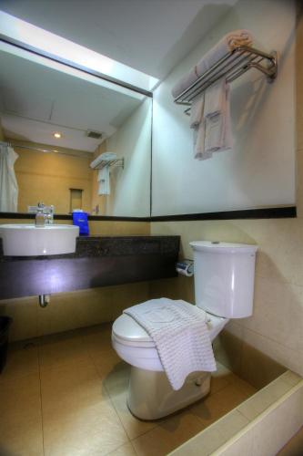 a bathroom with a toilet and a sink and a mirror at Fersal Hotel Neptune Makati in Manila