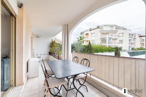 d'un balcon avec une table et des chaises noires. dans l'établissement Spacious apartment with pool located in the Marina of Mandelieu, à Mandelieu-la-Napoule