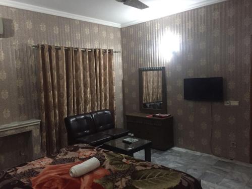 a room with a bed and a chair and a television at Star Hotel Lahore in Lahore