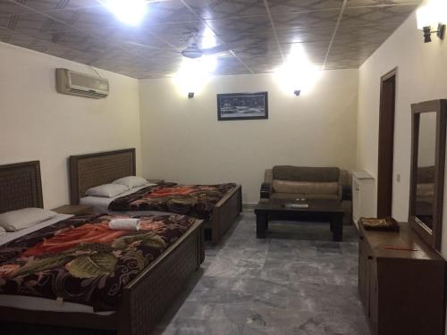 a room with two beds and a chair in it at Star Hotel Lahore in Lahore