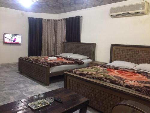 a hotel room with two beds and a table at Star Hotel Lahore in Lahore
