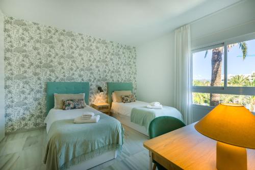 a room with two beds and a desk and a window at Apartamentos Urb, La Alcazaba 614 y 642 Banus Marbella in Marbella