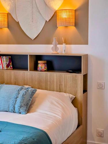 a bedroom with a wooden bed with two lights on the wall at Boho Nest in Rosporden