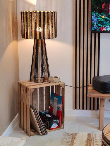 a table with a lamp on top of a wooden stand at Boho Nest in Rosporden