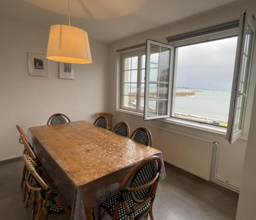 une salle à manger avec une table et des chaises et une fenêtre dans l'établissement Breizh Izel, vue mer et proche centre-ville, à Roscoff