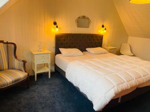 une chambre avec un grand lit blanc et une chaise dans l'établissement Breizh Izel, vue mer et proche centre-ville, à Roscoff