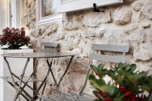two chairs and a table in front of a stone wall at Cozy Sommavilla Residence in Brenzone sul Garda