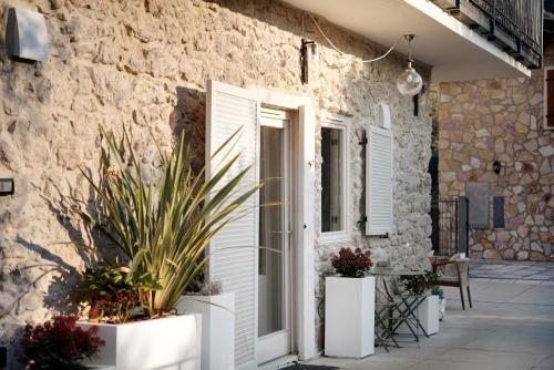 a stone house with white doors and potted plants at Cozy Sommavilla Residence in Brenzone sul Garda