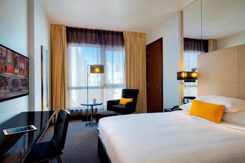 a hotel room with a bed and a desk and a chair at Centro Capital Doha - By Rotana in Doha