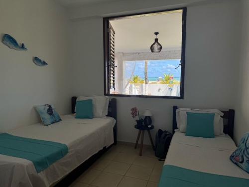 zwei Betten in einem Zimmer mit Fenster in der Unterkunft Casa Pé na Areia in São José da Coroa Grande