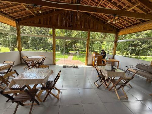 a room with tables and chairs and a person sitting at a table at Hospedaria Paiol in São Bento do Sapucaí