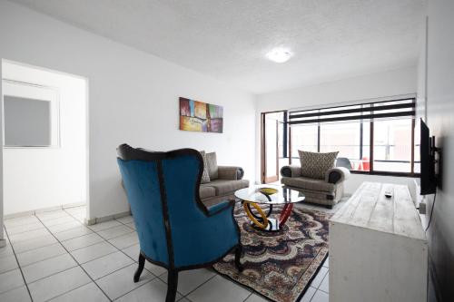 a living room with a blue chair and a table at Safi Luxury Apartment 2 in East London