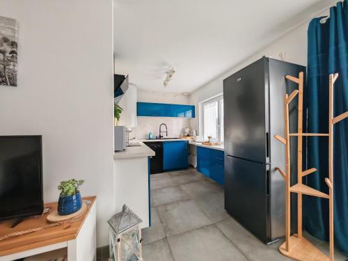 a kitchen with blue cabinets and a black refrigerator at Le cocon du Zoo de Beauval in Mareuil-sur-Cher