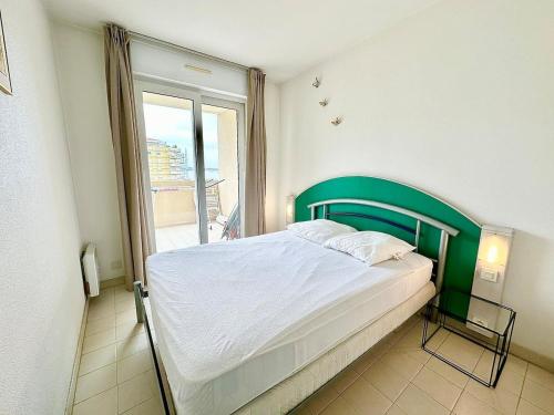 - une chambre avec un lit doté d'une tête de lit verte et d'une fenêtre dans l'établissement Appartement 1 chambre Vue mer piscine parking, au Golfe-Juan