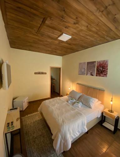 a bedroom with a large bed with a wooden ceiling at Hospedaria Paiol in São Bento do Sapucaí