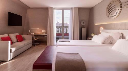 una habitación de hotel con dos camas y un sofá en NH Collection Porto Batalha, en Oporto