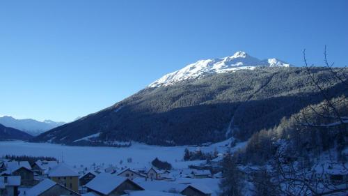 a snow covered mountain with a village and a lake at Reschnerhof in Resia