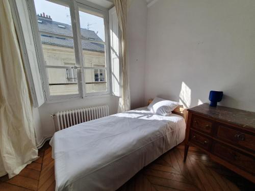 une chambre avec un lit et une grande fenêtre dans l'établissement EXIGEHOME-Appartement de standing au coeur de Versailles, à Versailles