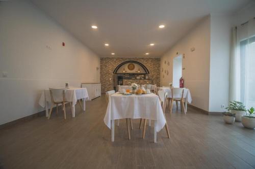 a dining room with white tables and white chairs at Vila Rosario in Ponta Delgada