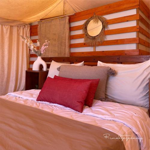 a bed with a red pillow on top of it at Rimal tata camp in Migourdâne