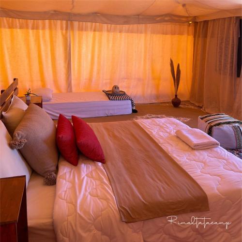 a bedroom with two beds with red pillows at Rimal tata camp in Migourdâne